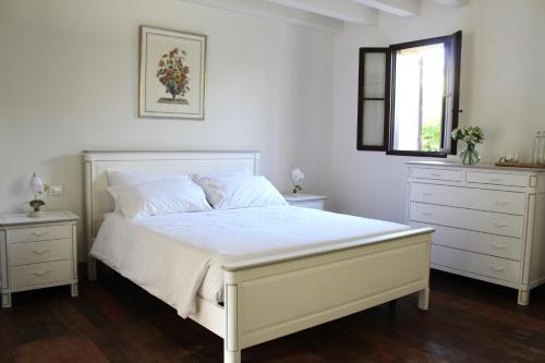 ein Schlafzimmer mit einem weißen Bett mit zwei Kommoden und einem Fenster in der Unterkunft Villa Trieste M in Asolo
