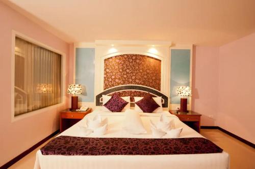 ein Schlafzimmer mit einem großen Bett und zwei Nachttischen in der Unterkunft Convenient Grand Hotel in Lat Krabang