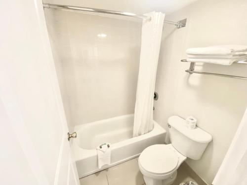 a white toilet sitting next to a bath tub at Garden Inn Homestead/Everglades/Gateway to Keys in Homestead