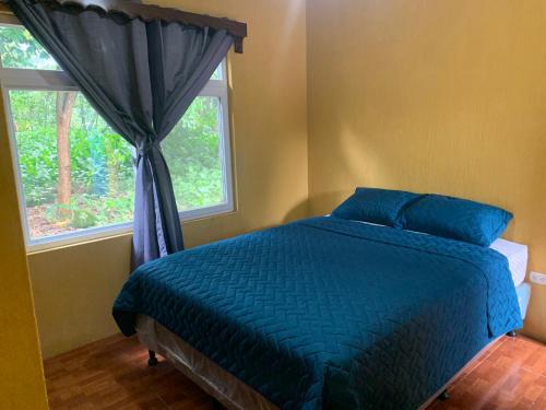 Un dormitorio con una cama azul y una ventana en Casa 3 a 5 min del Irtra, en Retalhuleu