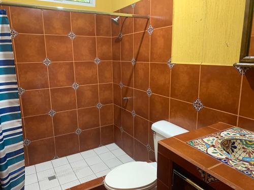 baño con aseo y pared de azulejos marrones en Casa 3 a 5 min del Irtra en Retalhuleu