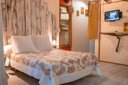 a bedroom with a bed with a tv on a wall at Douceur Tropicale Proximité plage et commerces in Punaauia