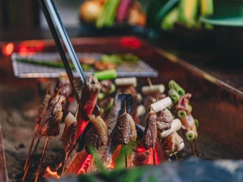 a bunch of food on a grill with tongs at Kominkayado LOOF Okanoie in Yamanashi