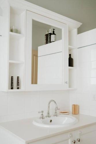 a white bathroom with a sink and a mirror at Cottage on Gray - Wangaratta in Wangaratta