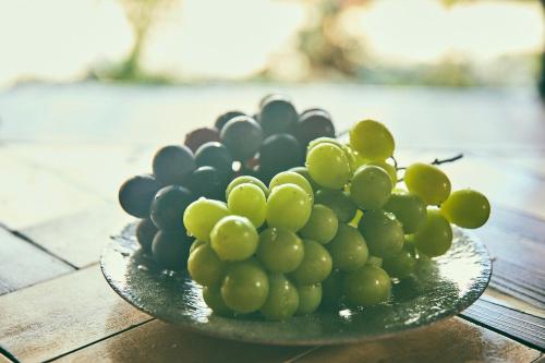 a plate of green grapes on a wooden table at Kominkayado LOOF Okanoie in Yamanashi