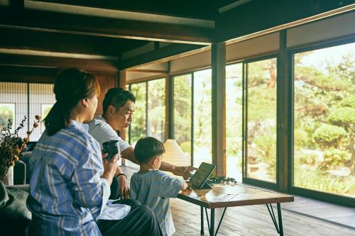 a group of people sitting around a table with a laptop at Kominkayado LOOF Okanoie in Yamanashi