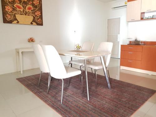 a dining room table with white chairs and a rug at Harmonize Hotel Chiang Mai in Chiang Mai