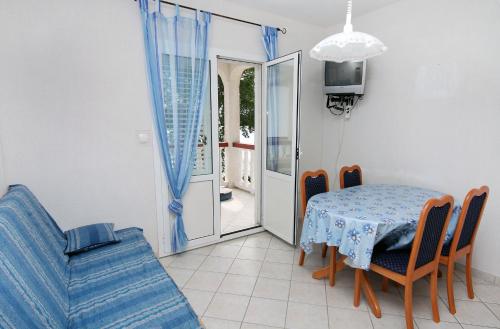 a dining room with a table and a blue couch at Apartments by the sea Supetarska Draga - Gornja, Rab - 2016 in Supetarska Draga