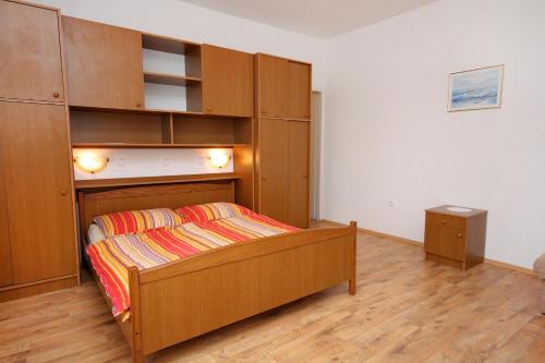 a bedroom with a bed and a wooden cabinet at Apartments by the sea Supetarska Draga - Gornja, Rab - 2016 in Supetarska Draga