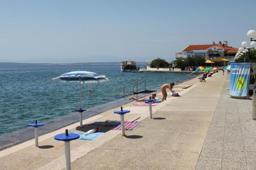 a group of people laying on the beach near the water at Triple Room Selce 2362c in Selce
