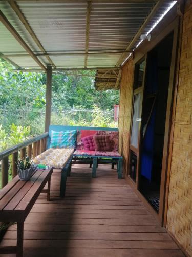 a wooden porch with a bench and a television at Genevieve Guest House and Tours in Siquijor