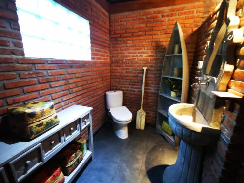 een bakstenen badkamer met een toilet en een wastafel bij Villa Kong in Amed