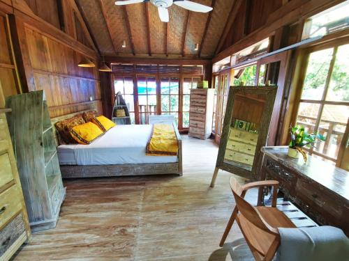 een slaapkamer met een bed, een bureau en ramen bij Villa Kong in Amed