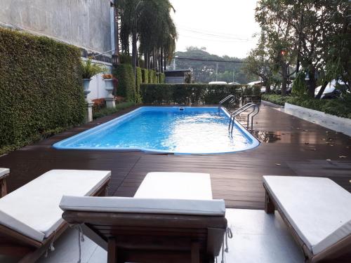 a swimming pool in a yard with two benches at Harmonize Hotel Chiang Mai in Chiang Mai