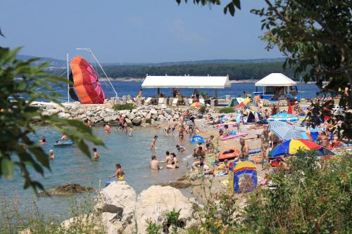 a bunch of people on a beach in the water at Apartments with a parking space Punat, Krk - 15451 in Punat