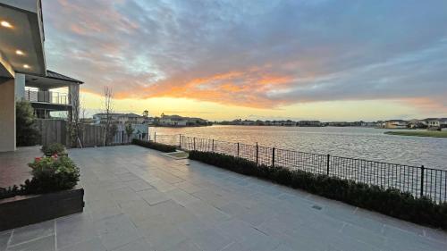 a sunset over a body of water next to a house at Luxury Waterfront Villa BBQ Cafe WiFi Great Views 5BRM in Point Cook