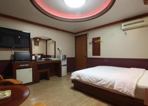 a bedroom with a bed and a table and a tv at Utopia Hotel in Gumi