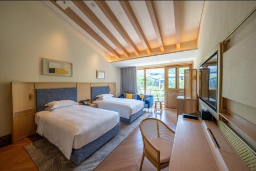una camera d'albergo con due letti e una televisione di voco Nanjing Garden Expo, an IHG Hotel a Nanjing