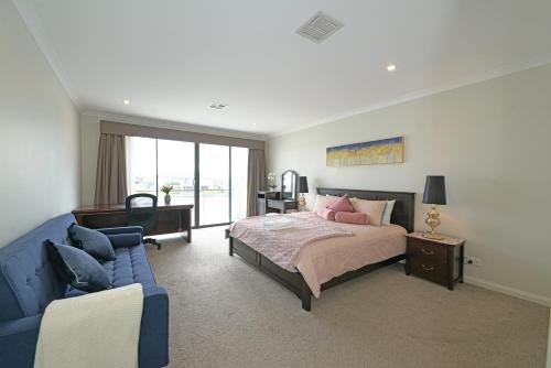a bedroom with a bed and a blue couch at Luxury Waterfront Villa BBQ Cafe WiFi Great Views 5BRM in Point Cook