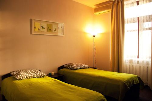 モスクワにあるILIAN Hostelのベッド2台、ランプ、窓が備わる客室です。