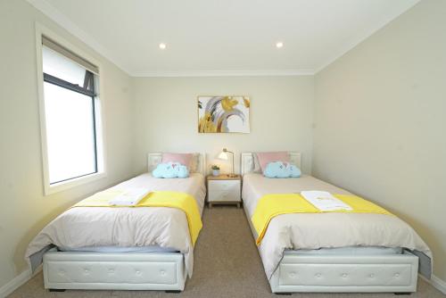 two beds in a room with two windows at Luxury Waterfront Villa BBQ Cafe WiFi Great Views 5BRM in Point Cook