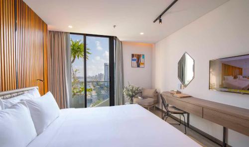 a bedroom with a bed and a desk with a mirror at HAIAN Riverfront Hotel Da Nang in Da Nang