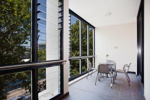- une salle à manger avec de grandes fenêtres, une table et des chaises dans l'établissement KULA North Sydney, à Sydney