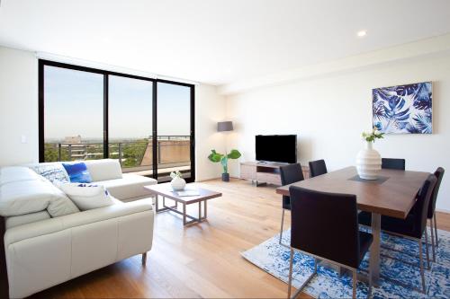 a living room with a white couch and a table at KULA North Sydney in Sydney