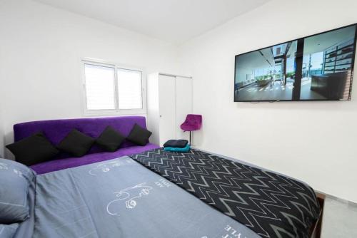 a bedroom with a purple couch and a flat screen tv at New! luxus- Best suit 2 minutes fromTel Aviv in Bat Yam
