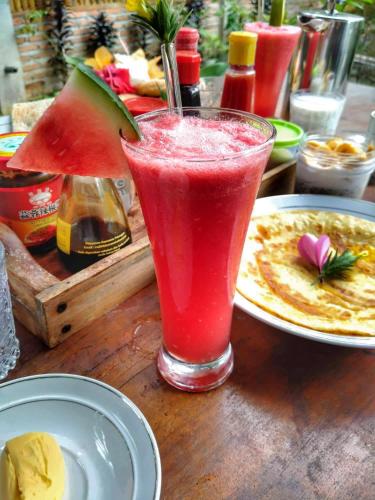 a drink sitting on a table with a slice of watermelon at Sumatra Orangutan Discovery Villa in Bukit Lawang