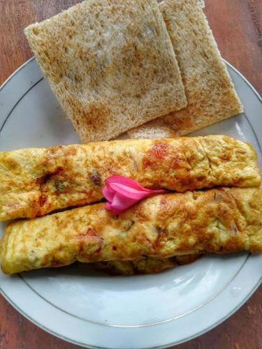 a white plate with three omelets and some bread at Sumatra Orangutan Discovery Villa in Bukit Lawang