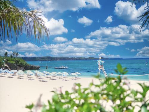 einen Strand mit Liegestühlen und Sonnenschirmen und dem Meer in der Unterkunft Pension Moon Villa in Onna