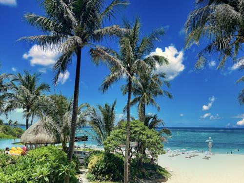 einen Strand mit Palmen und dem Meer in der Unterkunft Pension Moon Villa in Onna