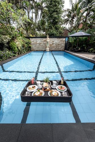 una bandeja de comida junto a la piscina en Gunung Merta Bungalows, en Ubud