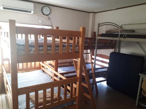 two bunk beds in a room with a clock on the wall at Guest House Nagasaki Vogelnest in Nagasaki