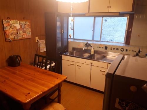 a kitchen with a sink and a wooden table at Guest House Nagasaki Vogelnest in Nagasaki
