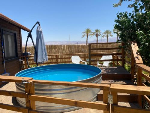 a hot tub on a deck with an umbrella at ווילו בערבה in ‘En Yahav