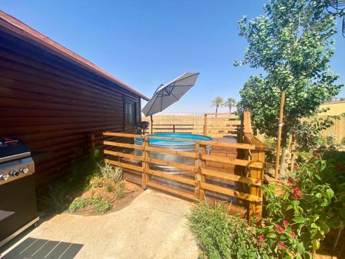 a fence with an umbrella next to a swimming pool at ווילו בערבה in ‘En Yahav