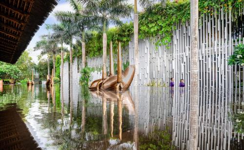 a fence with a statue in front of a body of water at Naman Retreat in Da Nang