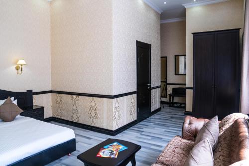 um quarto de hotel com uma cama, um sofá e uma mesa em Belon Lux Hotel em Astana