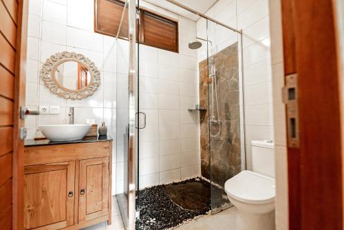 a bathroom with a shower and a toilet and a sink at Gunung Merta Bungalows in Ubud