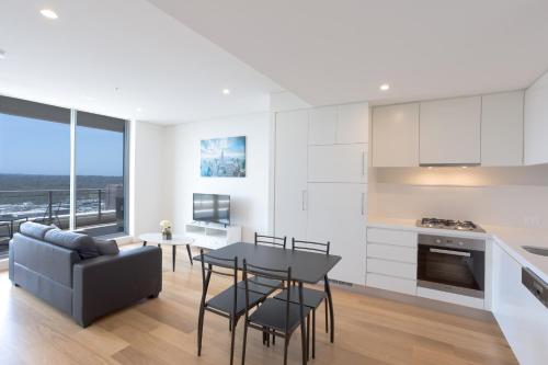 a kitchen and living room with a table and chairs at KULA Macquarie Park in Sydney