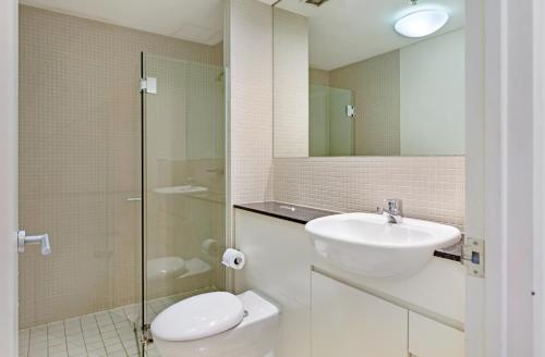 a bathroom with a sink and a toilet and a mirror at KULA North Sydney-Napier in Sydney