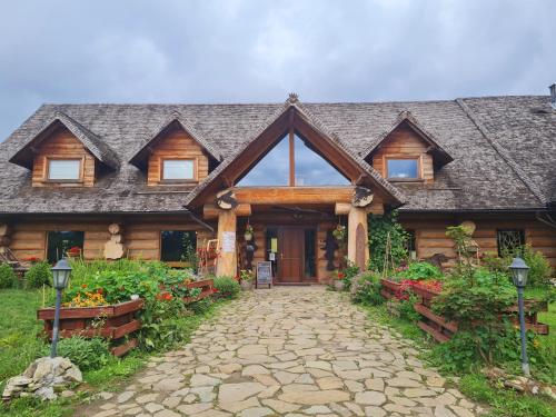 a log home with a stone pathway in front of it at Wilcza Jama - domki z bali in Lutowiska