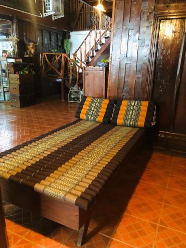 a large wooden bench in a room with a staircase at Banthai Guesthouse in Phetchaburi