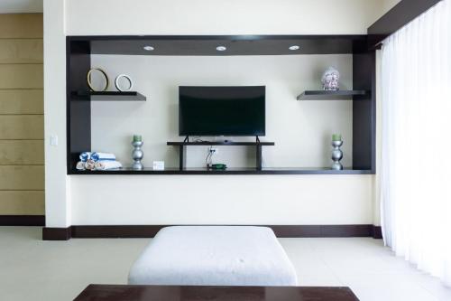 a living room with a tv and a couch at Aldea Beachside Condo by BVR in Playa del Carmen