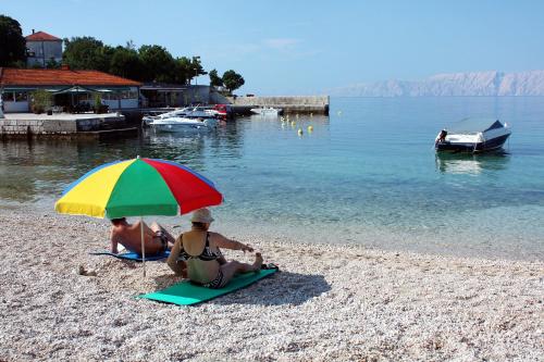 two people sitting on the beach under an umbrella at Apartments with parking space Povile, Novi Vinodolski - 2398 in Povile