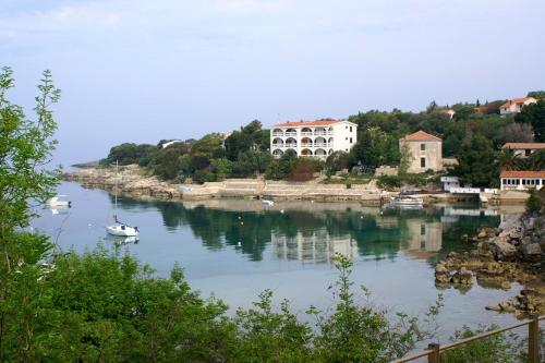 un petit bateau dans une rivière avec des maisons sur une colline dans l'établissement Apartment Potocnica 4096e, à Stara Novalja