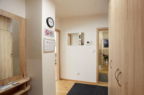 baño con lavabo y reloj en la pared en Apartment Rezidence - Javor & Wellness en Železná Ruda