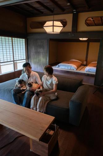 a group of three people sitting on a couch in a room at Kominkayado LOOF Sannoie in Koike